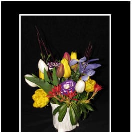 Mixed bouquet of tulips and other flowers in a white vase