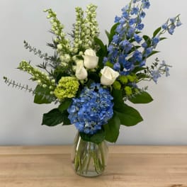 Blue and white floral arrangement in a clear glass vase