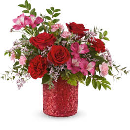 Red and pink mixed flower arrangement in a glittery red vase