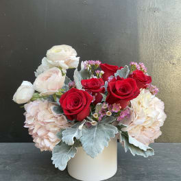 Red and white roses with pale pink blooms in a white vase