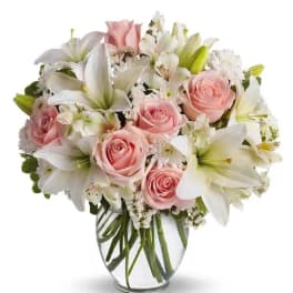 Pink roses and white lilies arranged in a clear glass vase