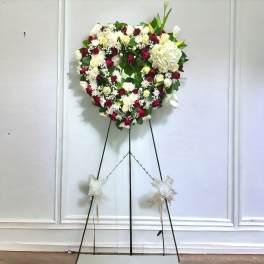 Heart-shaped floral wreath on a standing easel with red and white flowers