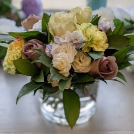 Bouquet of cream and mauve roses with pale carnations in a glass vase