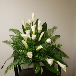 White calla lilies and roses in a lush green arrangement