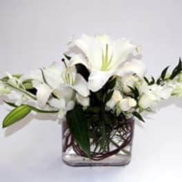 White lilies arranged in a clear square vase