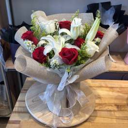 Bouquet of red roses and white lilies wrapped in beige paper