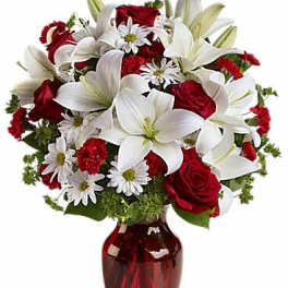Bouquet of red roses and white lilies in a red glass vase