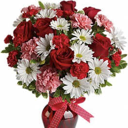 Red roses and white daisies in a red vase with a polka-dot ribbon