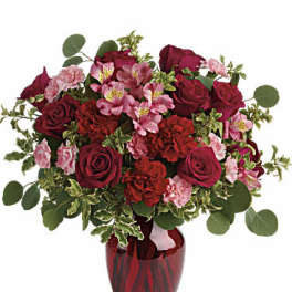 Red roses and pink flowers in a red glass vase