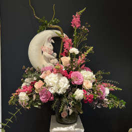Pink and white floral arrangement with a rabbit figurine in a glass vase