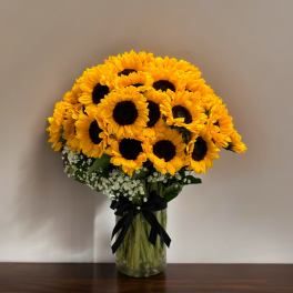 Bouquet of yellow sunflowers in a glass vase with a black ribbon