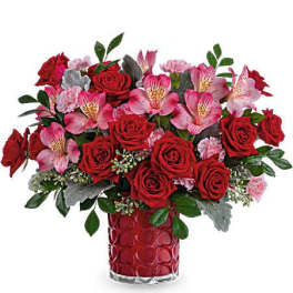 Red roses and pink alstroemeria in a red glass vase