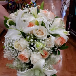 Cascade bouquet of white lilies and peach roses with baby's breath
