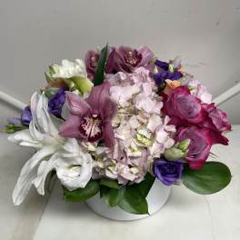 Mixed bouquet with pink roses, hydrangea, orchids, and white lilies in a white vase
