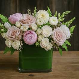Pink and white roses arranged in a green glass vase
