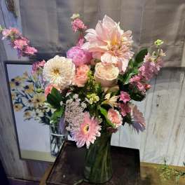 Pastel pink and white mixed flower arrangement with dahlias, roses, and gerberas in a clear glass vase