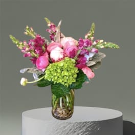 Pink and magenta bouquet in a glass vase with green blooms