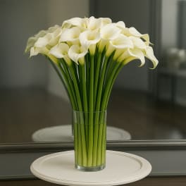 White calla lilies arranged in a clear glass vase