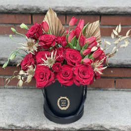 Red roses and pink tulips arranged in a black hatbox