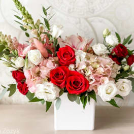 Red and white roses with pink blooms in a white vase