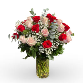 Red and blush roses arranged in a clear glass vase