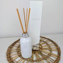 White reed diffuser bottle with a tall box and bamboo sticks
