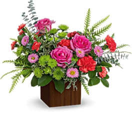 Pink and red mixed flower arrangement in a wooden cube vase