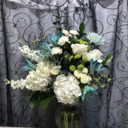 White floral arrangement in a glass vase with blue accents