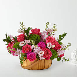 Pink roses and carnations in a woven basket with green pom-pom flowers
