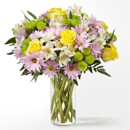 Bouquet of yellow roses, pink daisies, and white alstroemeria in a glass vase
