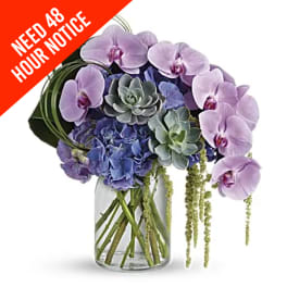 Lavender orchids and blue hydrangeas in a glass vase