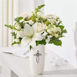 White floral arrangement in a tall vase with a cross emblem