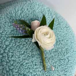 Small boutonniere with a white bloom and purple accent flowers