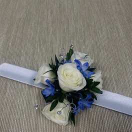 White rose corsage with blue flowers and a white ribbon