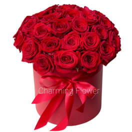 Red roses arranged in a round hatbox with a satin ribbon