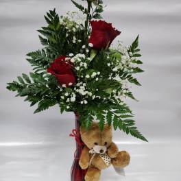 Red roses in a tall vase with baby's breath and a teddy bear
