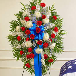 Standing floral spray with red and white flowers and a blue ribbon