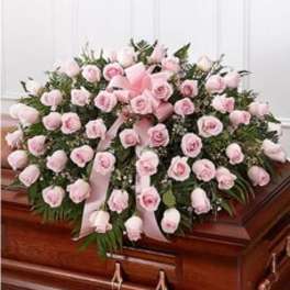 Pink rose casket spray with ribbon on a wooden casket