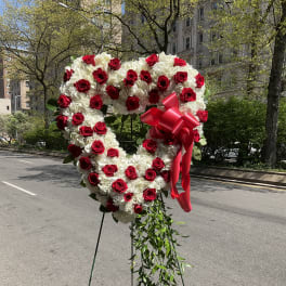 Heart-shaped red and white floral standing arrangement with ribbon