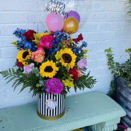 Birthday flower arrangement with balloons in a striped box