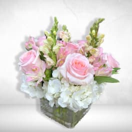 Pink roses and white hydrangeas in a clear square vase