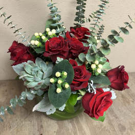 Red roses arranged with eucalyptus and a succulent in a green vase