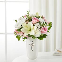 Pink roses and white lilies in a white vase with a cross emblem