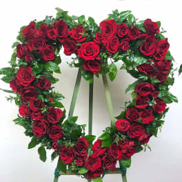 Heart-shaped wreath of red roses displayed on a standing easel