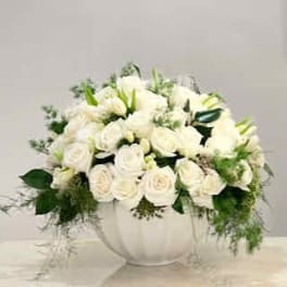 White rose arrangement in a white vase with trailing greenery
