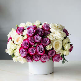 Bouquet of pink, purple, and white roses in a white box