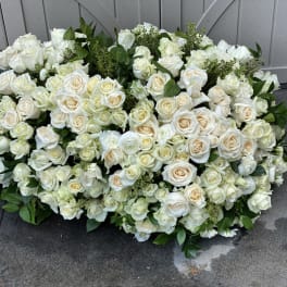 Large white rose arrangement with greenery on the ground