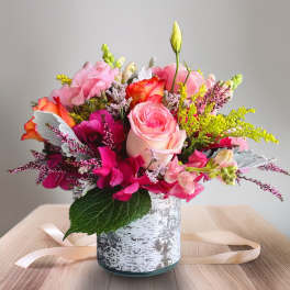 Pink and orange mixed bouquet in a white patterned vase