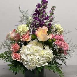 Mixed bouquet of pink, white, and purple flowers in a black vase