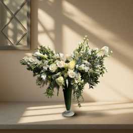 Large white floral arrangement in a tall green vase
